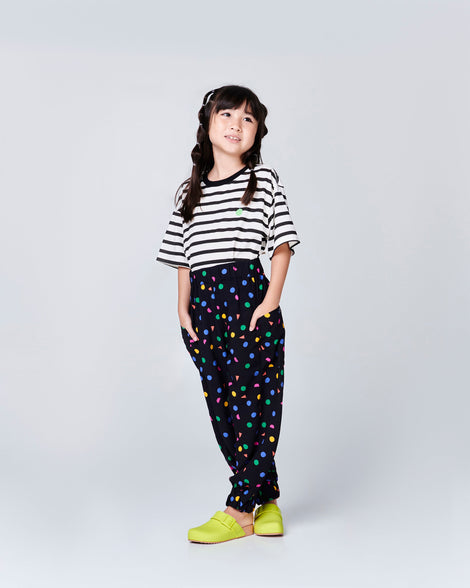 Child model in a black pants wearing a pair of kids green Cozy Clog