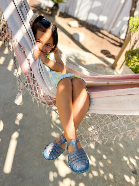 young girl wearing the blue glitter possession sandals