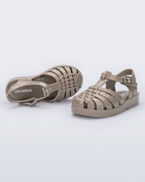 Top and angled view of a pair of glitter beige baby Possession fisherman style sandals