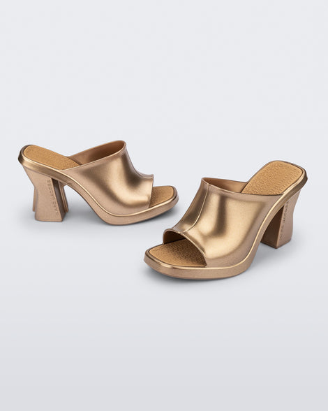 Side and angled view of a pair of gold Mule + Marc Jacobs heels.