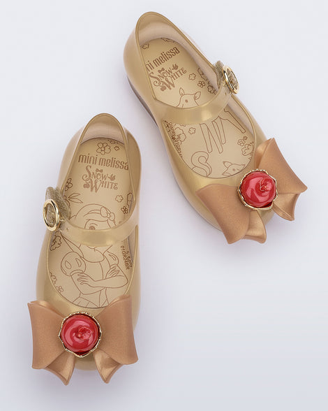 Top view of a pair of beige Sweet Love Snow White baby flats with a beige bow with red apple center