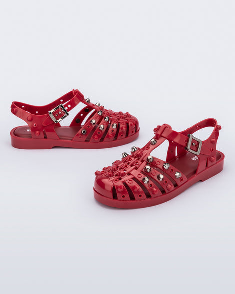 Side and angled view of a pair of red Possession Studs fisherman sandals with silver studs.