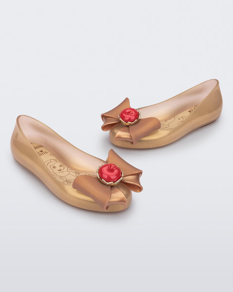 Angled view of a pair of beige Sweet Love Snow White kids flats with a beige bow with red apple center