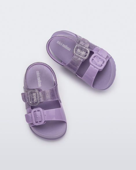 Top view of a pair of lilac glitter Mini Melissa Cozy sandals with with two front straps with buckle detail