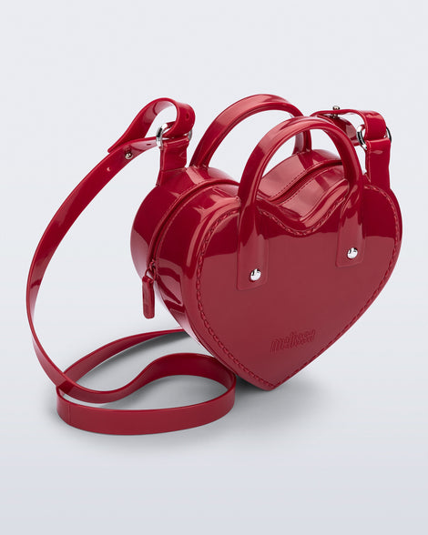 Angled view of a red Heartbeat bag with small handles and longer strap.