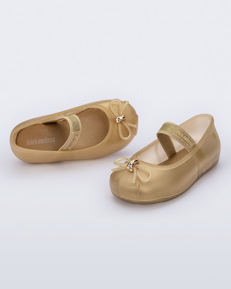 Side and angled view of a pair of pearly beige Sophie baby ballerina flats with bow