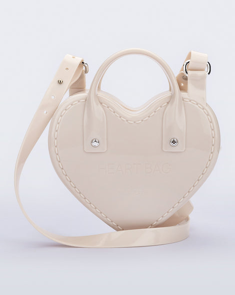 Back view of a beige Heartbeat bag with small handles and longer strap.