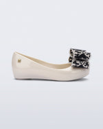 Side view of a beige kids Ultragirl Classic Bow kids flats with black and clear bow