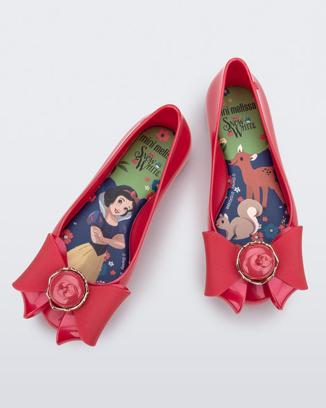 Top view of a pair of red Sweet Love Snow White kids flats with a red bow with red apple center