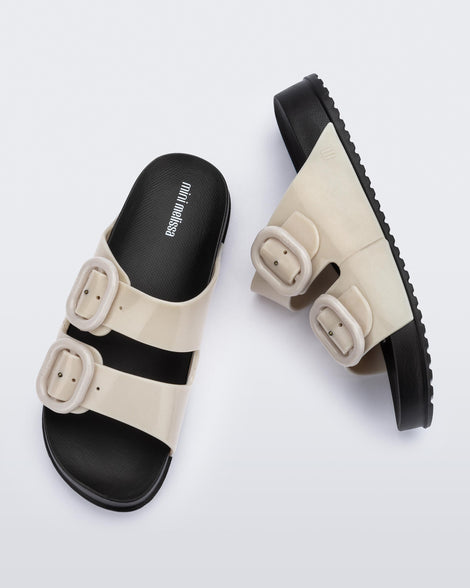 Top and side view of a pair of kids beige Cozy slides with black sole