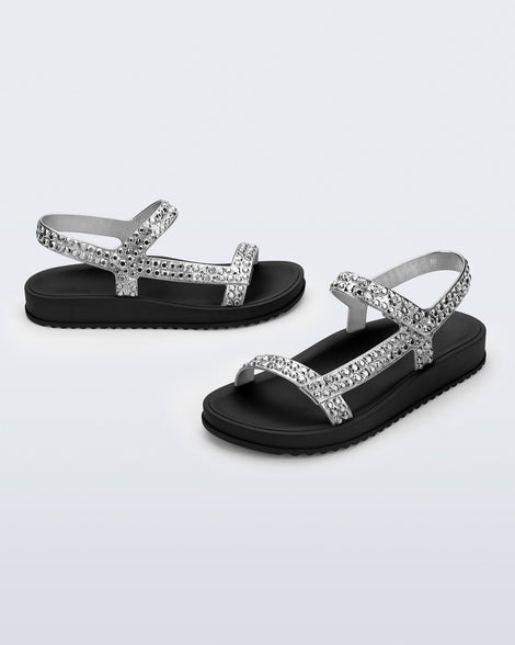 Side and angled view of a pair of black Lust sandals with silver strap