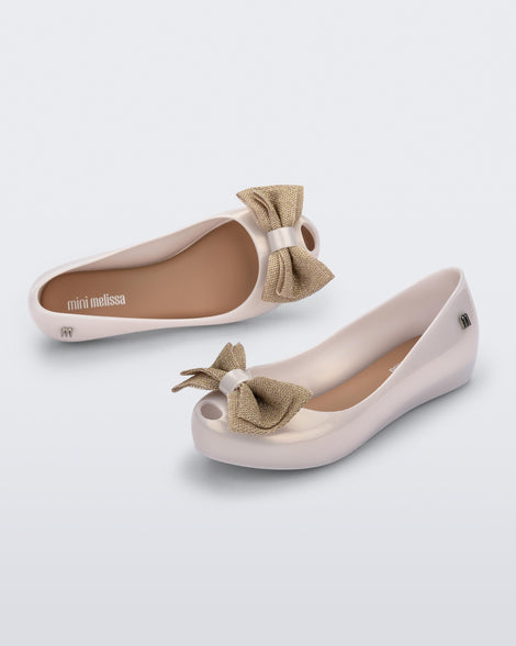 Angled view of a pair of pearly beige Ultragirl Sweet kids ballerina flats with bow