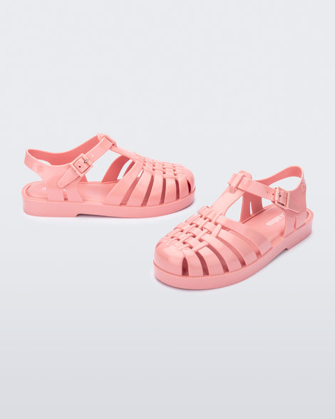 Side and angled view of a pair of light pink kids Possession sandals.