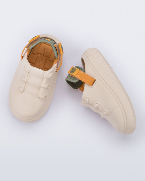 Side and top view of a pair of beige with orange and green back strap Charlie baby sneakers