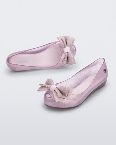 Angled view of a pair of glitter pink Ultragirl Sweet kids ballerina flats with bow