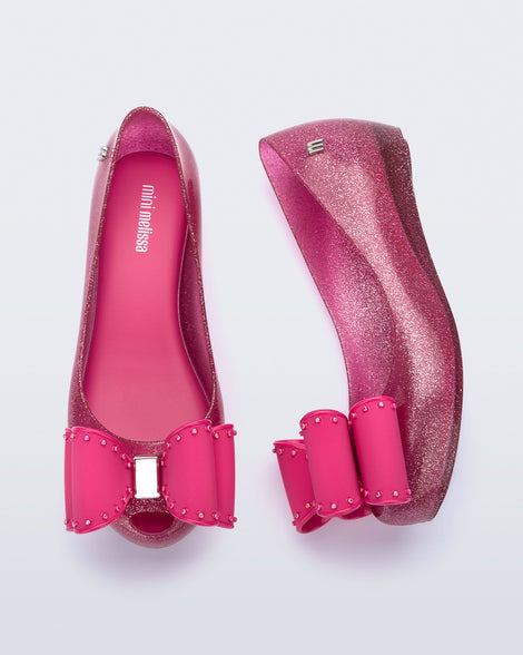 Top and side view of a pair of glitter pink kids Ultragirl Classic Bow kids flats