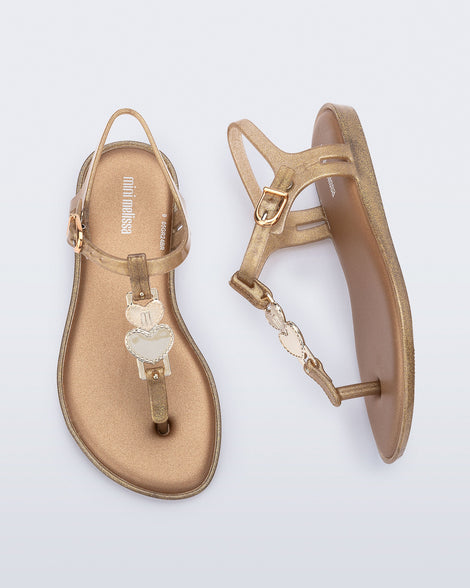 Top and side view of a pair of gold glitter Solar kids sandal with a heart embellishment