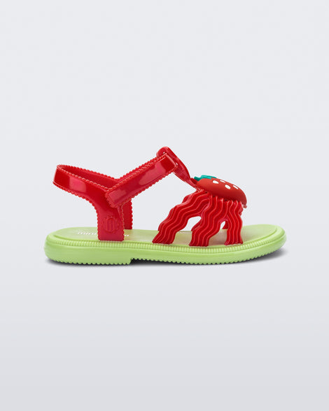 Side view of a red baby Hip Sandal with red strawberry and green sole