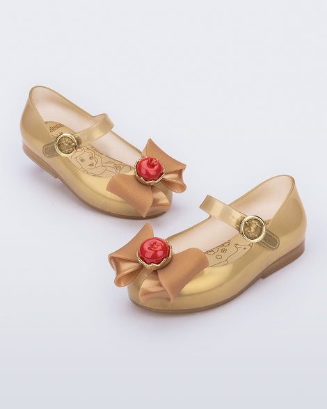 Angled view of a pair of beige Sweet Love Snow White baby flats with a beige bow with red apple center