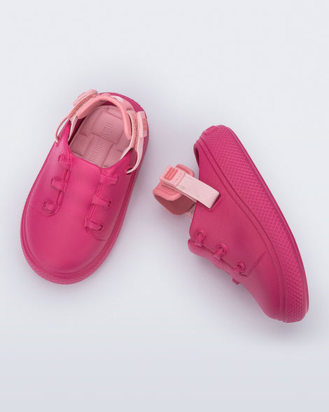 Side and top view of a pair of pink with back strap Charlie baby sneakers