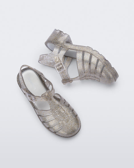 Top and side view of a pair of clear glitter gold kids Possession Heel sandals