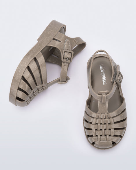 Top and angled view of a pair of glitter beige baby Possession fisherman style sandals