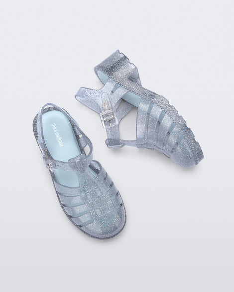 Top and side view of a pair of clear glitter kids Possession Heel sandals