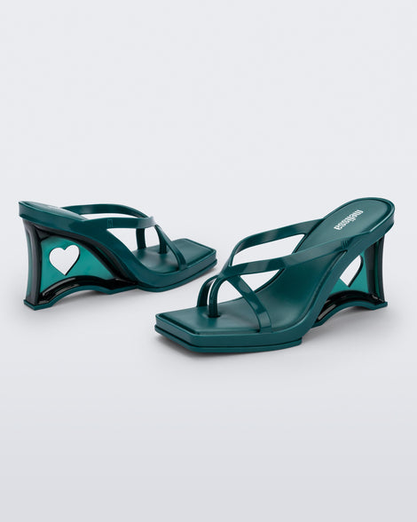 Side and angled view of a pair of green Glass Heels with a heart cutout in the heel.