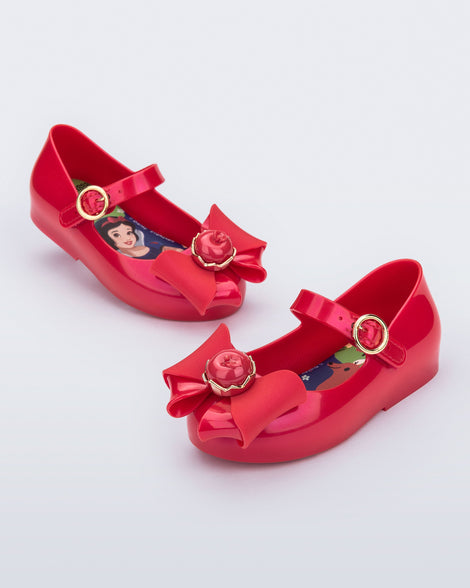 Angled view of a pair of red Sweet Love Snow White baby flats with a red bow with red apple center