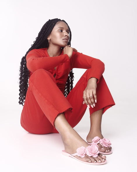 Model wearing a red outfit and a pair of pink Harmonic Springtime women's flip flop with 3 pink flowers.