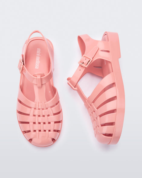 Side and top view of a pair of light pink kids Possession sandals.