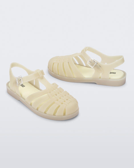 Side angled view of a pair of light beige Possession sandals