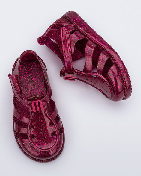 Top and side view of a pair of glitter pink baby Hip Daydream sandals