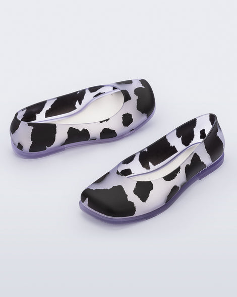 Angled view of a pair of clear Ruby adult flats with black splashes.