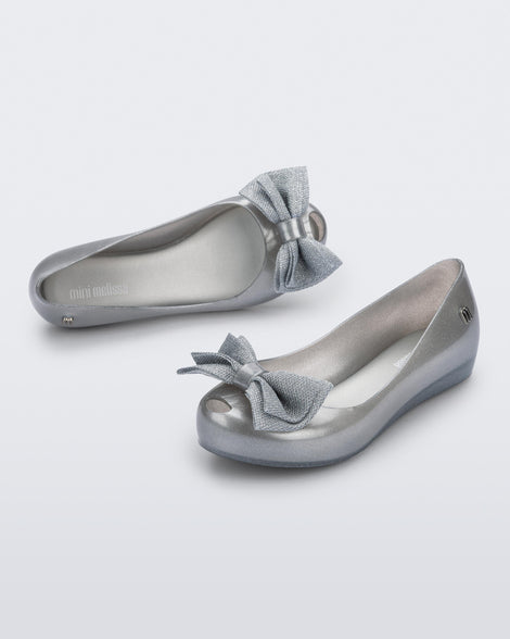 Angled view of a pair of pearly silver Ultragirl Sweet kids ballerina flats with bow