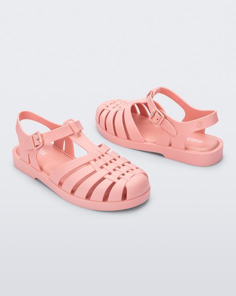 Side angled view of a pair of light pink Possession sandals