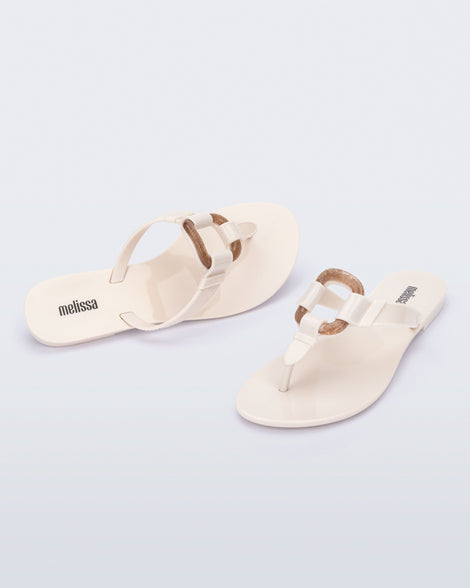 Angled view of a pair of beige Olivia adult flip flops