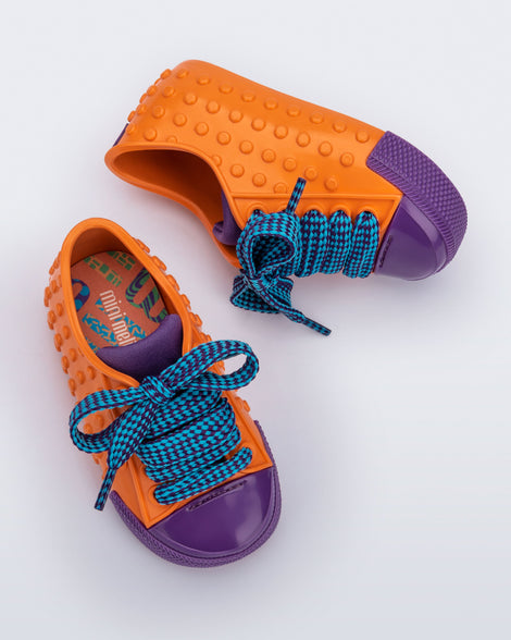 Top and side view of a pair of orange and purple Polibolha baby sneakers with blue laces.