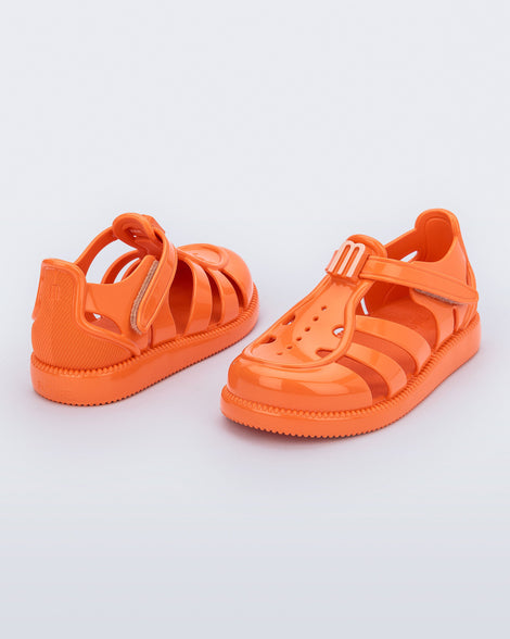 Back and angled view of a pair of orange baby Hip Daydream sandals