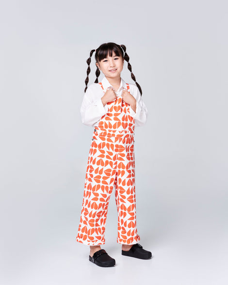 Child model in a orange and white outfit wearing a pair of black kids Cozy Clogs