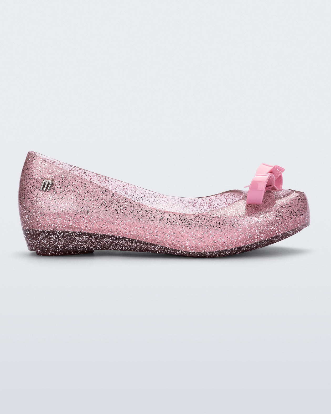 Side view of a Glitter Pink Mini Melissa Ultragirl Bow Glitter flat with a pink glitter base and pink bow