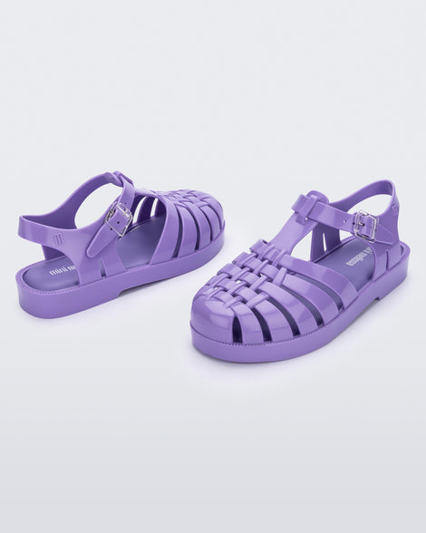 An angled side and back view of a pair of lilac Mini Melissa Possession sandals with several straps and a lilac base.