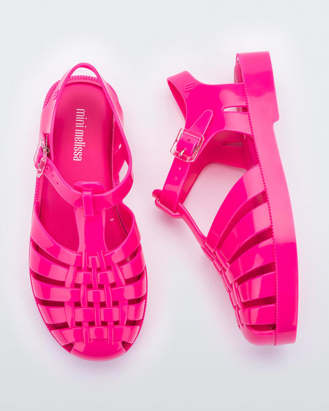 A top and side view of a pair of pink Mini Melissa Possession sandals with several straps, a closed toe front and a back ankle strap.