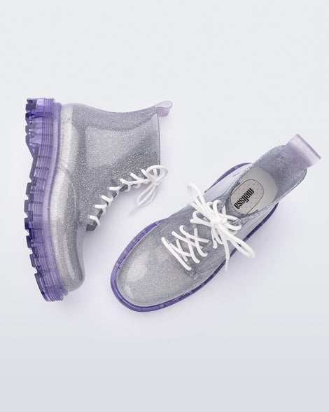 A top and side view of a pair of lilac/silver glitter Melissa Coturno with a clear silver glitter base, white laces and a lilac sole.