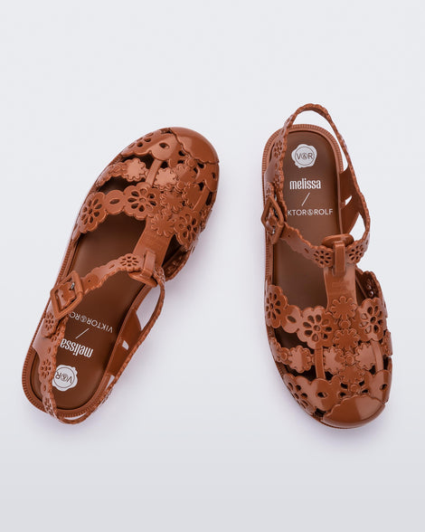 Top view of a pair of Melissa Possession fisherman sandals in brown with cut out lace detail on the straps.