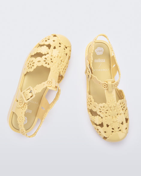 Top and angled view of a pair of Melissa Possession fisherman sandals in yellow with cut out lace detail on the straps.