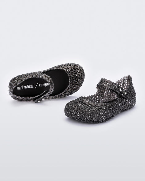 A pair of Mini Melissa Campana black glitter flats with a strap with snap closure for baby with an open woven texture