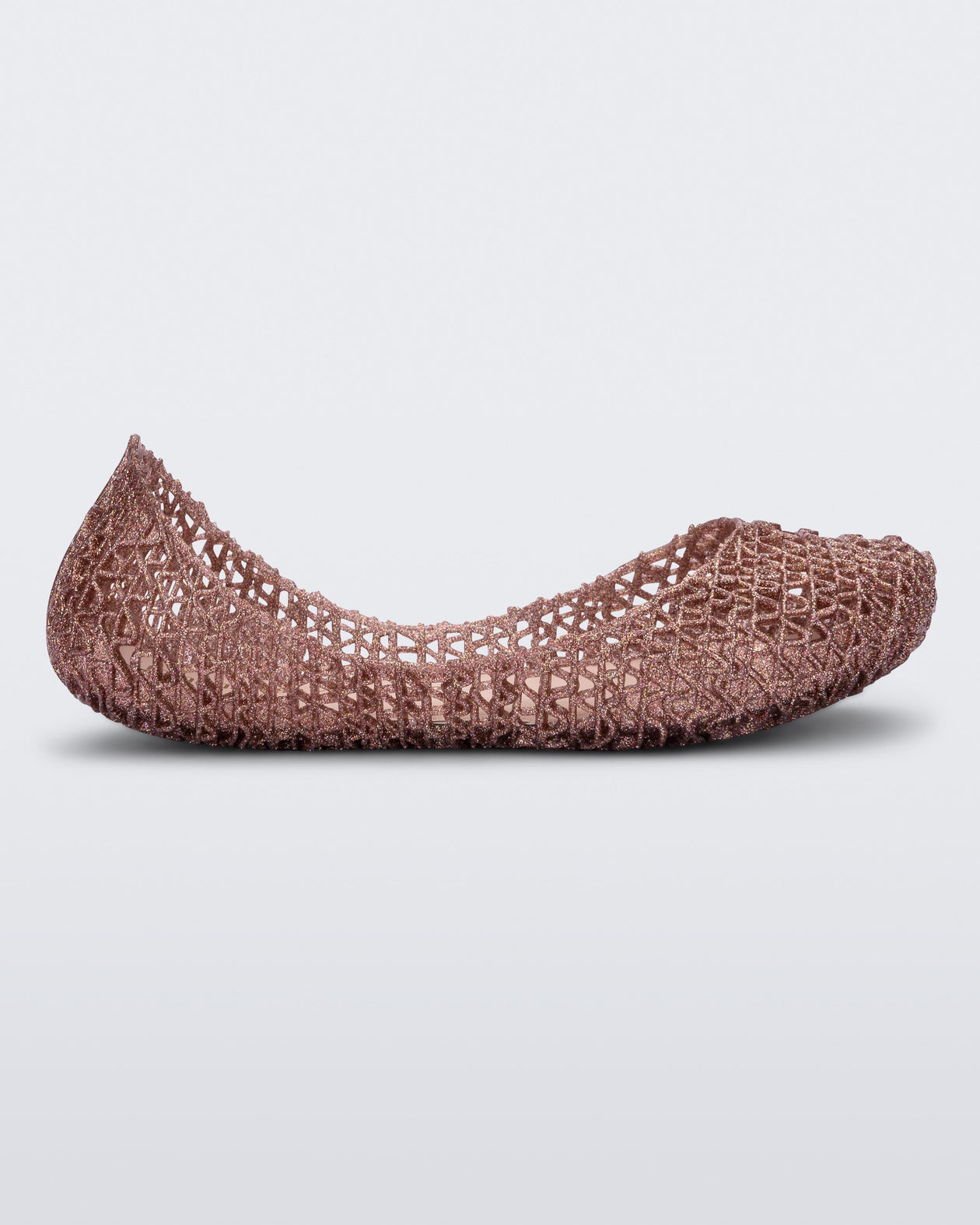 Side view of a light pink glitter Mini Melissa Campana flat with an open woven texture.