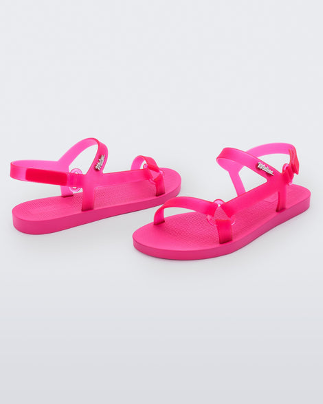 Angled view of a pair of Melissa Sun Downtown sandals with transparent pink front cross and back ankle straps and a pink sole. 