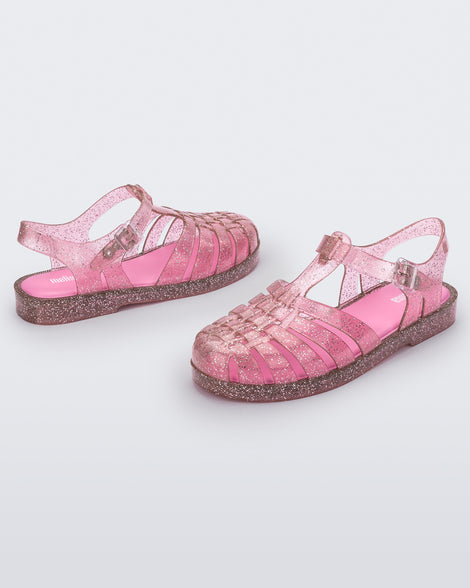 A side view of a pair of pink glitter Melissa Possession Shiny sandals with several straps and a closed toe front.
